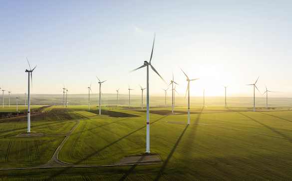 Aerial view of wind turbines made using plastic, backlit by evening light.